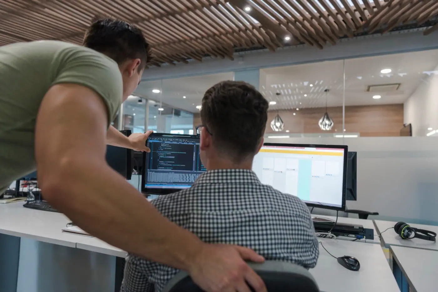 Zwei Männer schauen gemeinsam auf einen Bildschirm mit Programmcode.