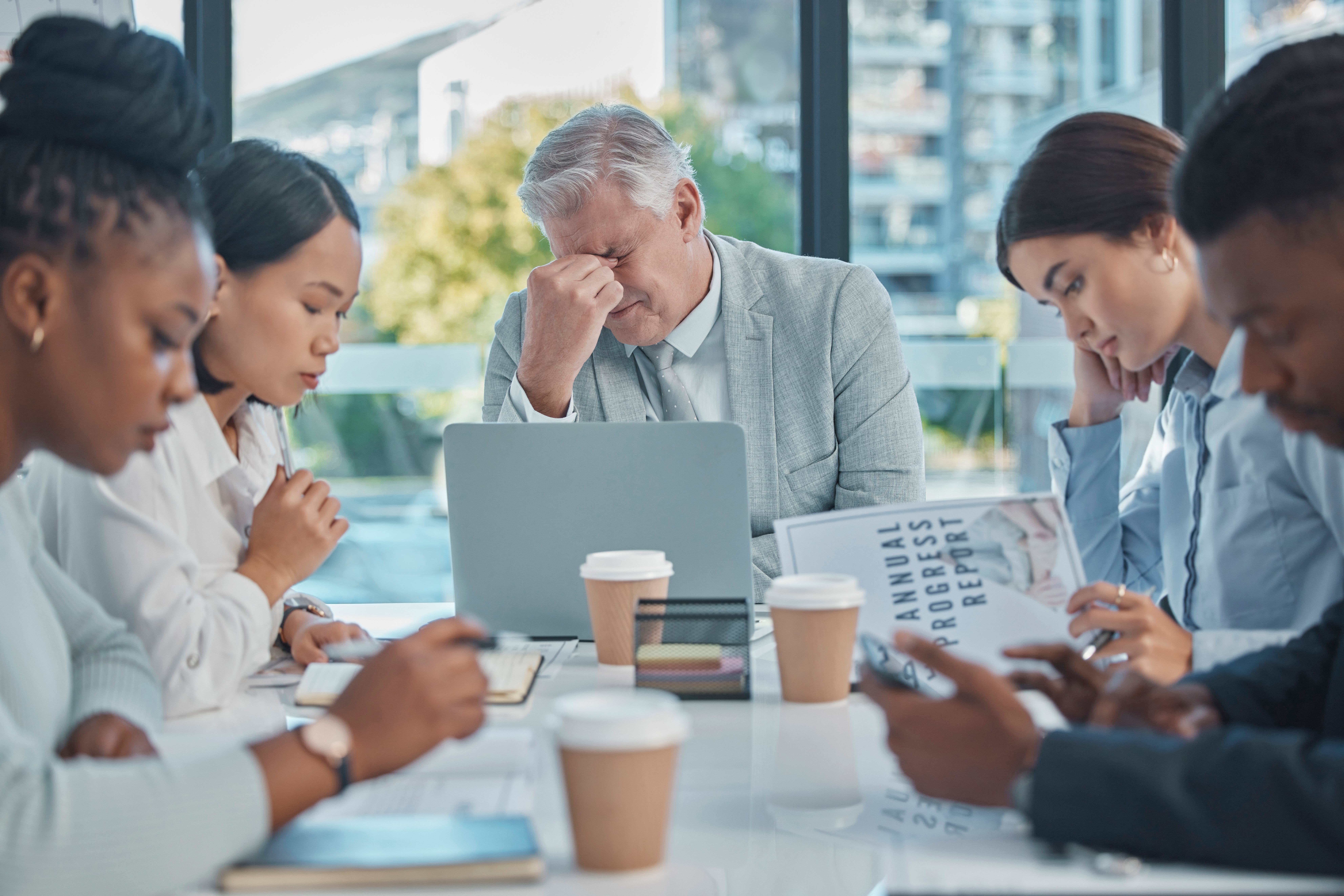 Gestresstes Team arbeitet an einem Report und zeigt ineffiziente Unternehmensprozesse